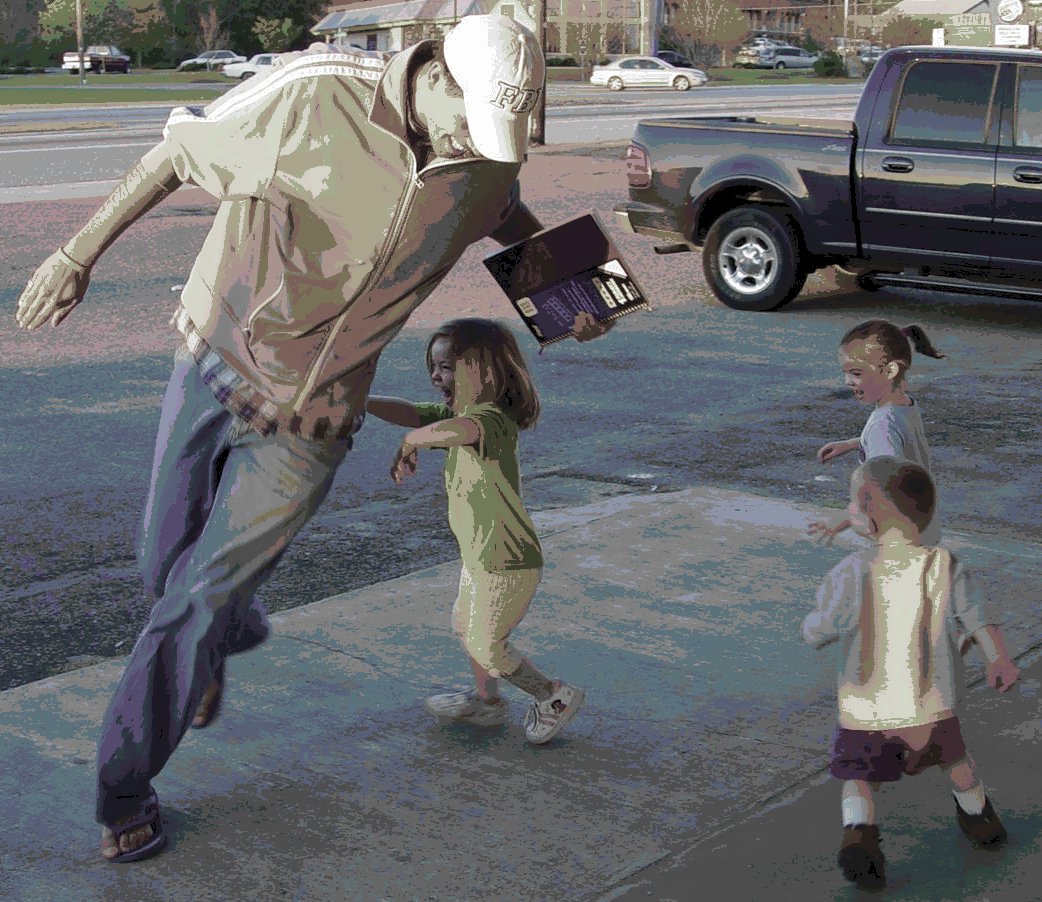 Three small kids chasing a tall man around in a small circle