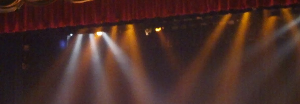 Stage lights shining from behind as the curtain rises.